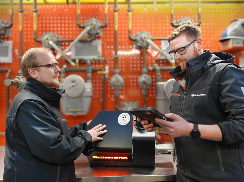 Zwei Entwicklungsingenieure von Schwank mit dem Brenner eines Wasserstoff Dunkelstrahlers.